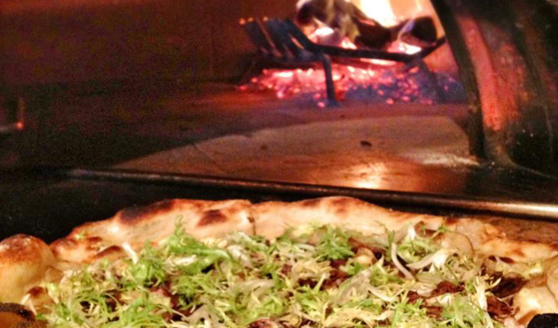 pizza coming out of the open fire oven