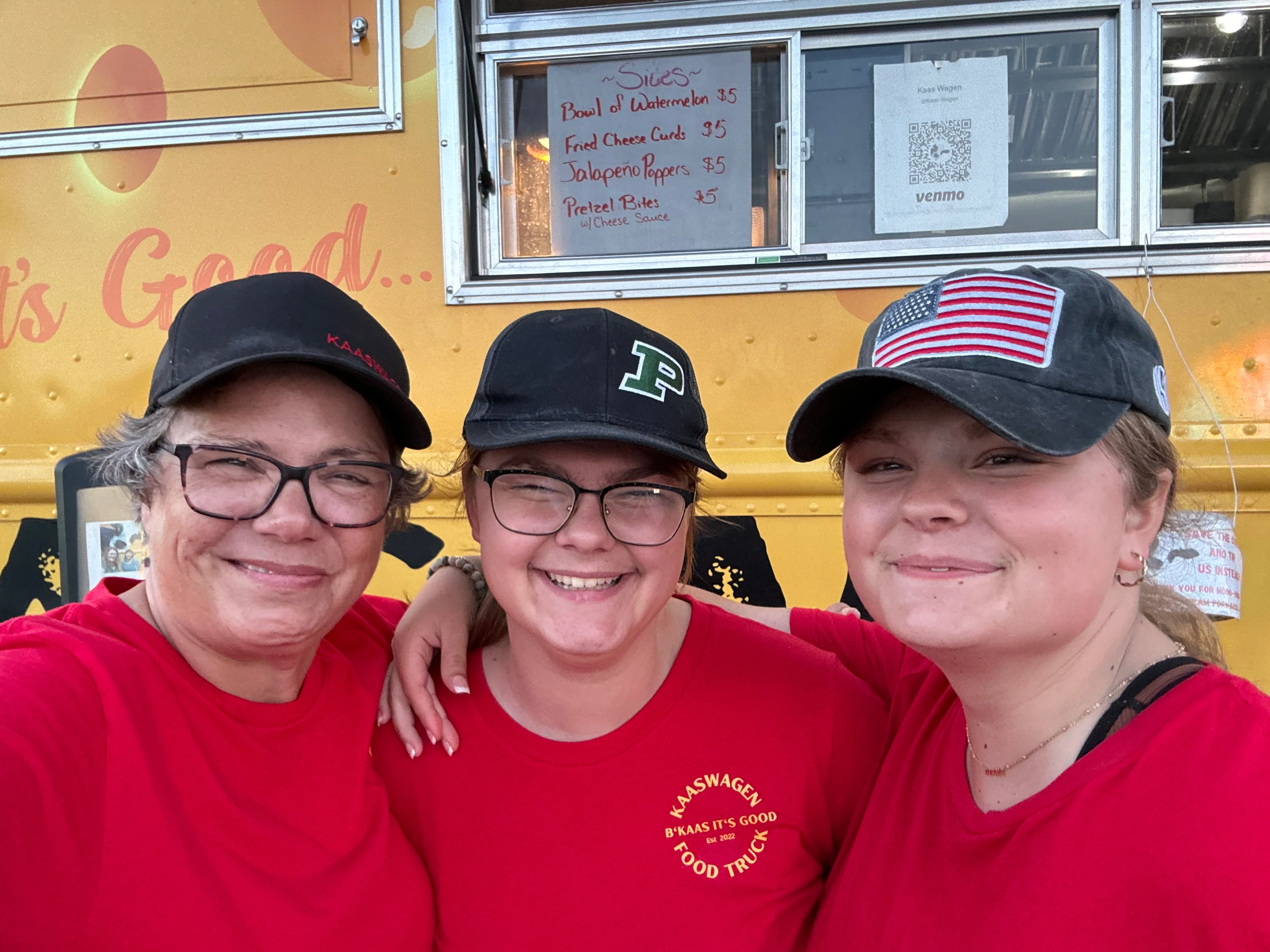 Food truck staff smiling in front of their vibrant food truck