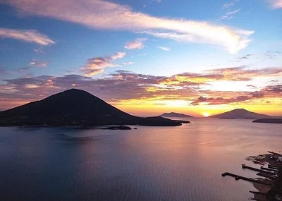 Sunset over a tranquil coastal bay with silhouetted mountains