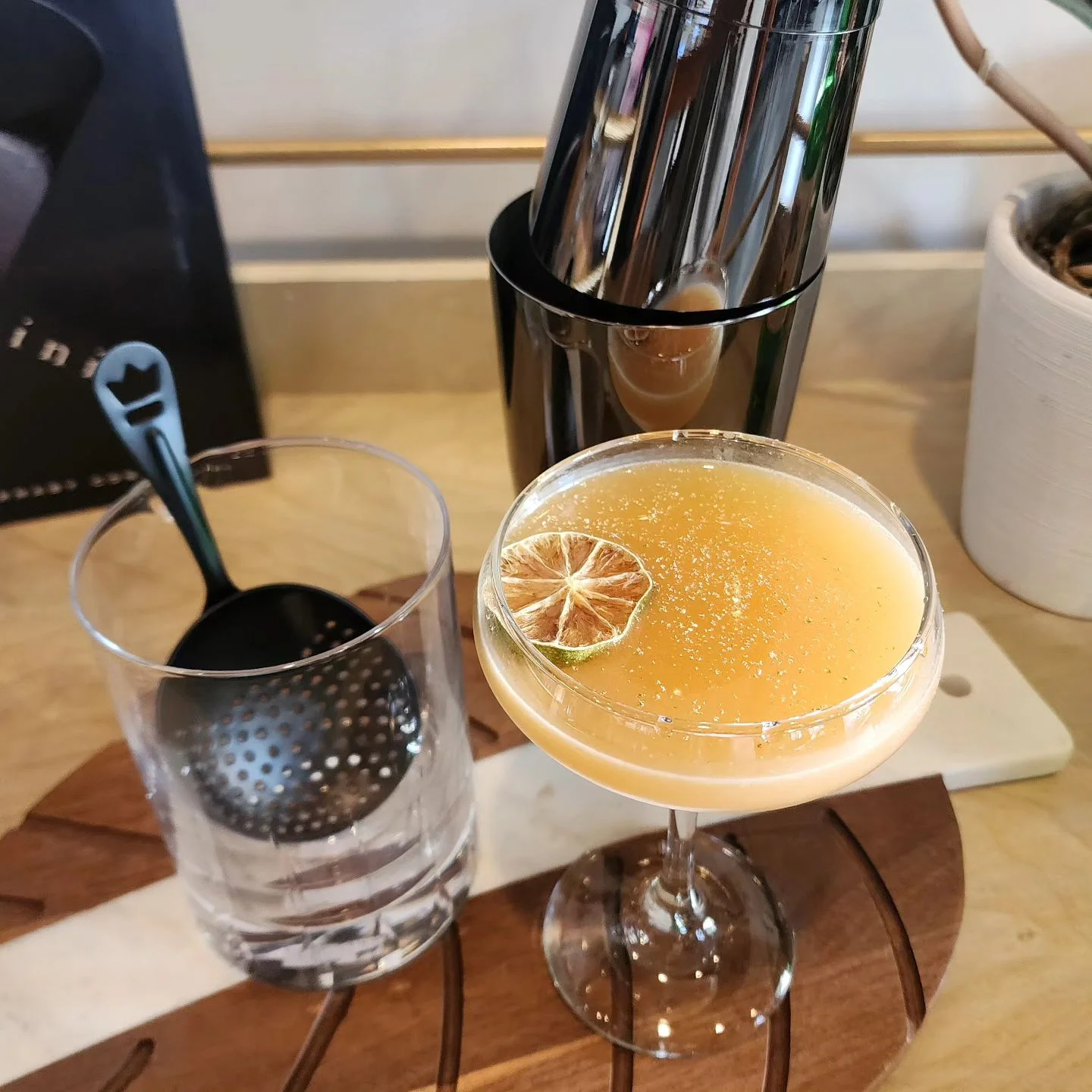 Craft cocktail served in a coupe glass with a dried lime garnish
