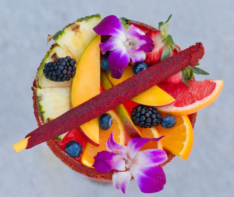 Colorful fruit cocktail garnished with edible flowers