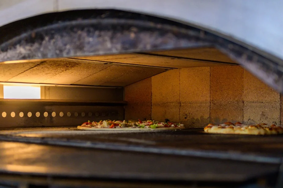 Wood-fired oven baking Margherita pizza