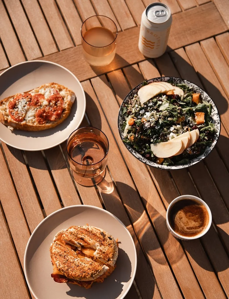 Artisan bagel sandwich and fresh salad on a wooden table