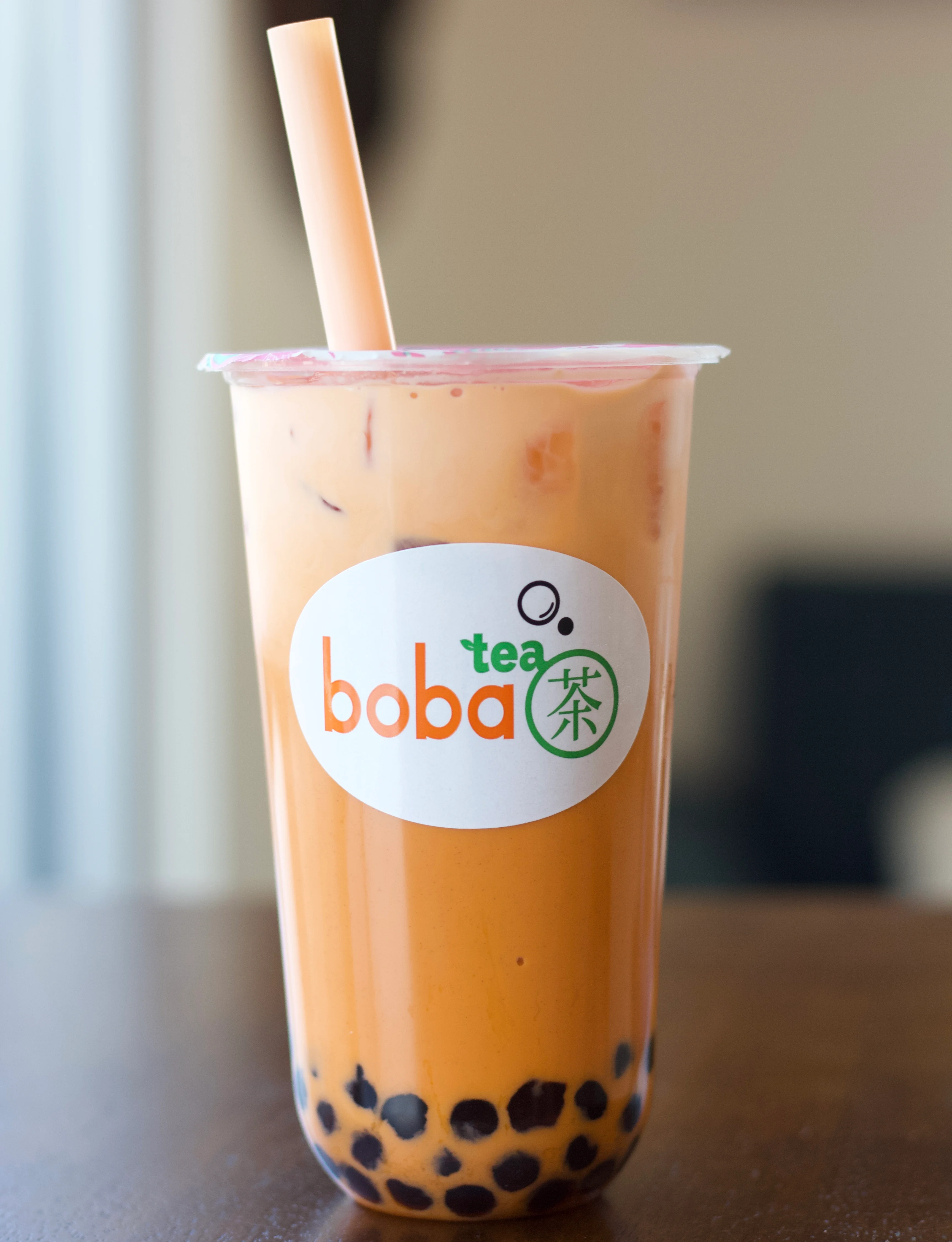 Two cups of boba tea placed side by side on a table. One features a creamy caramel layer, and the other is a sweet purple drink.