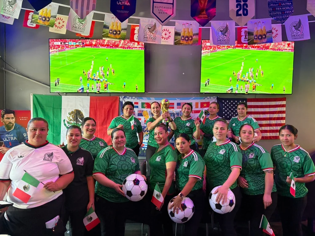 Group of fans celebrating soccer with flags and jerseys in a lively restaurant