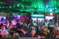 Lively bar scene with patrons enjoying drinks under green lights