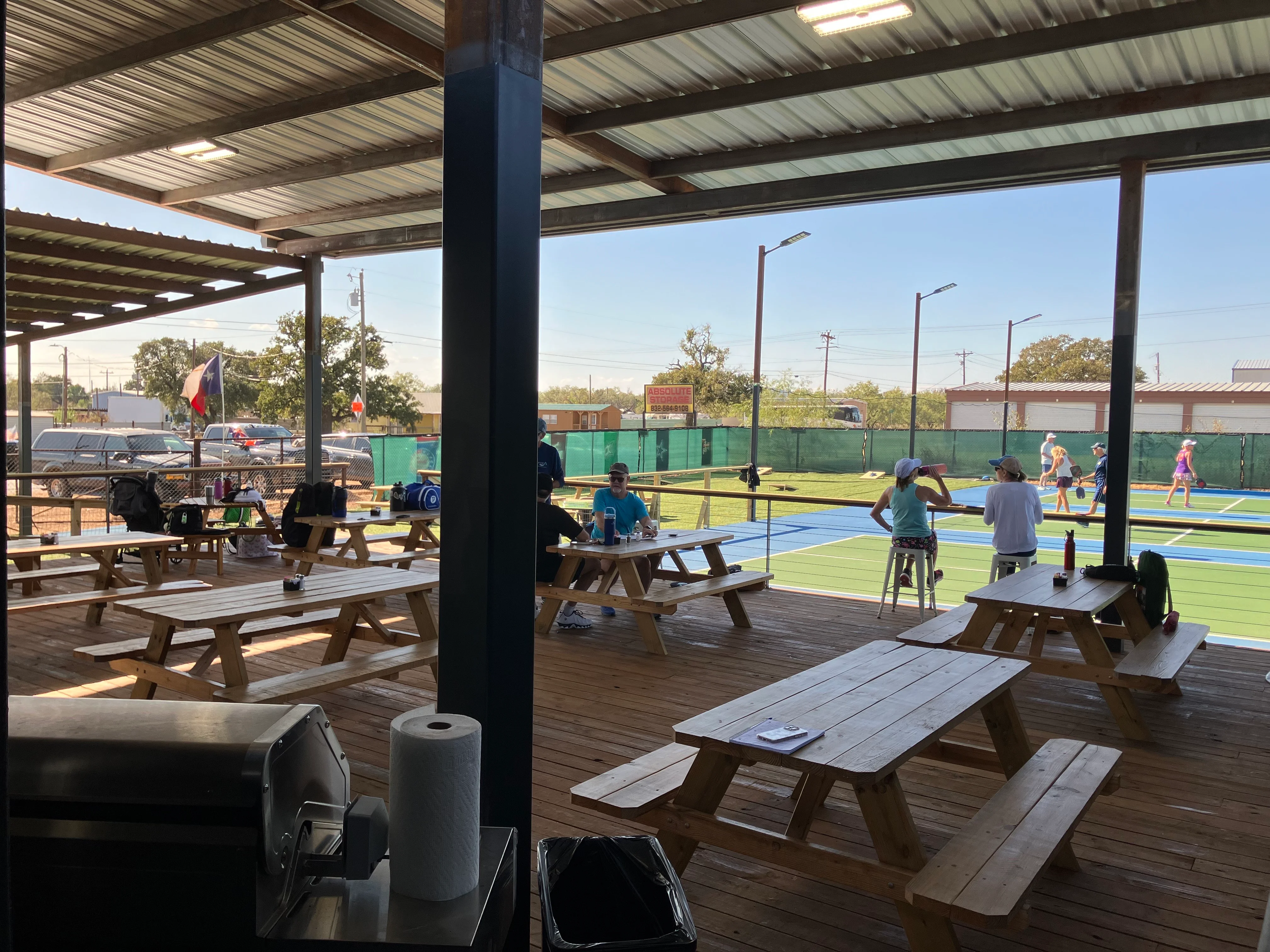 Outdoor dining area with picnic tables and pickleball courts