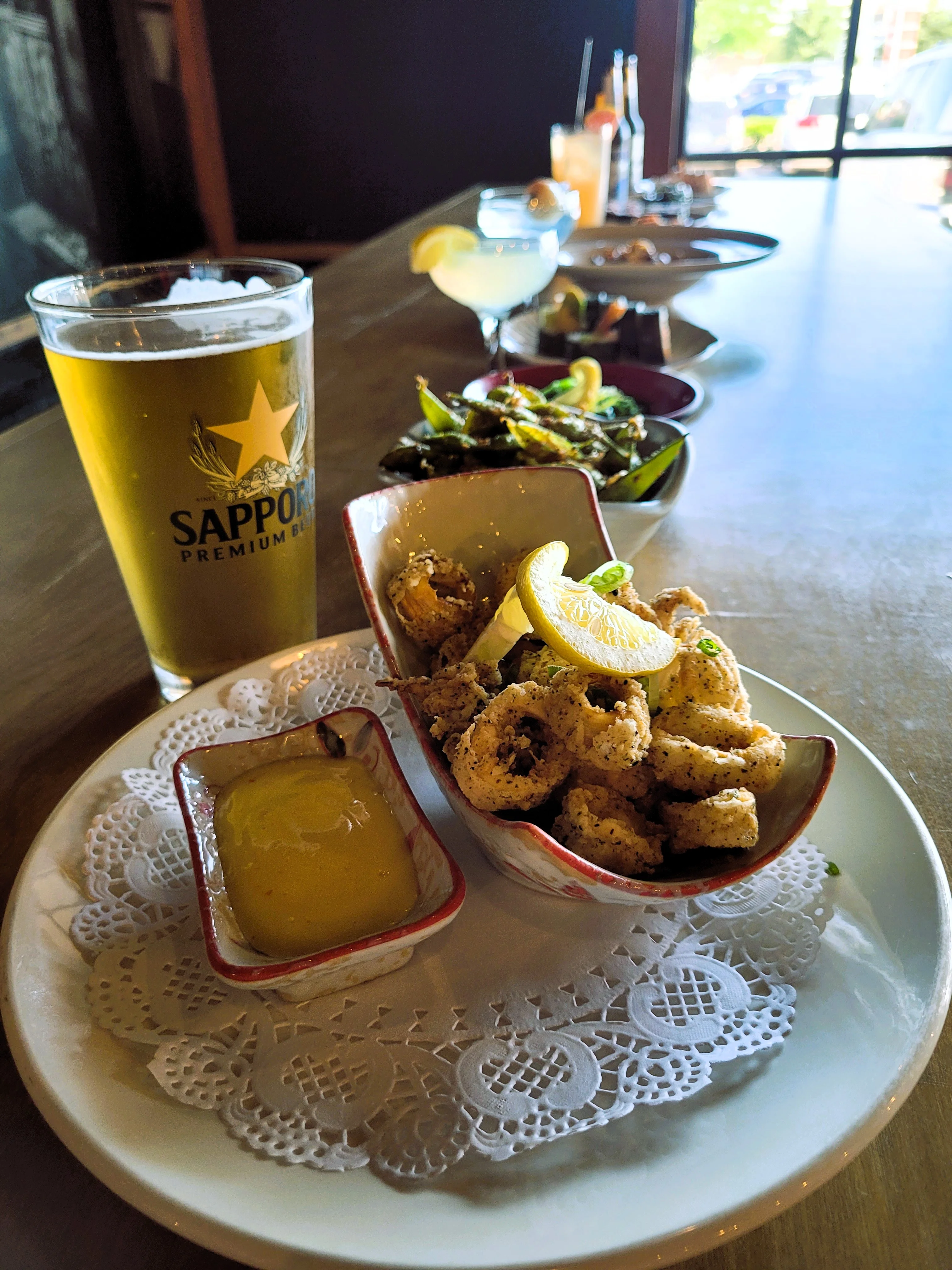 Crispy calamari with lemon and dipping sauce in a vibrant bar setting