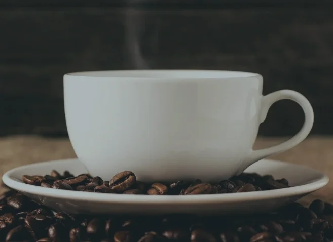 Steaming cup of coffee on roasted coffee beans