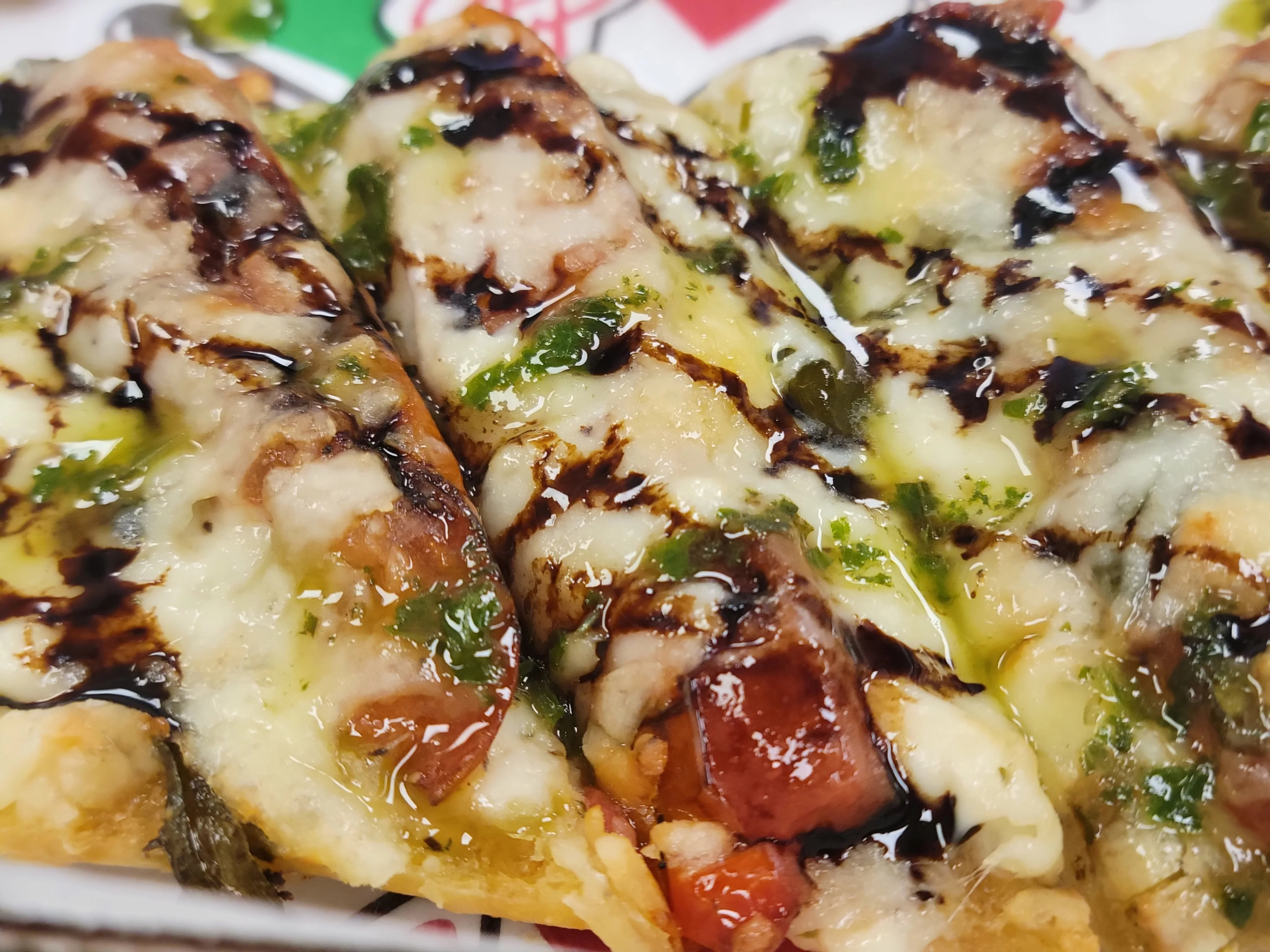 Close-up of a dish featuring grilled meats wrapped in a tortilla, topped with melted cheese and a drizzle of sauce.