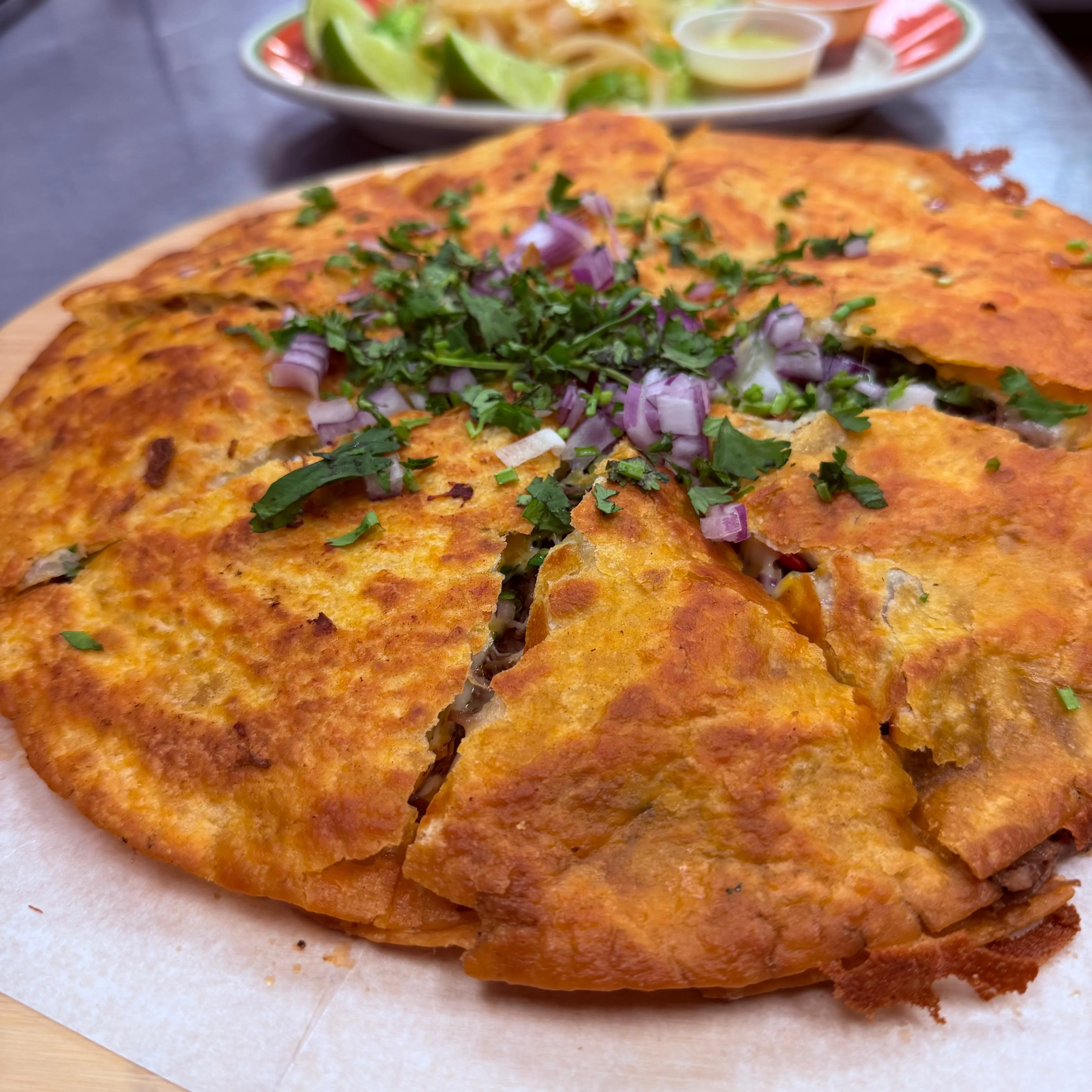 Delicious Mexican quesadilla topped with fresh herbs and onions
