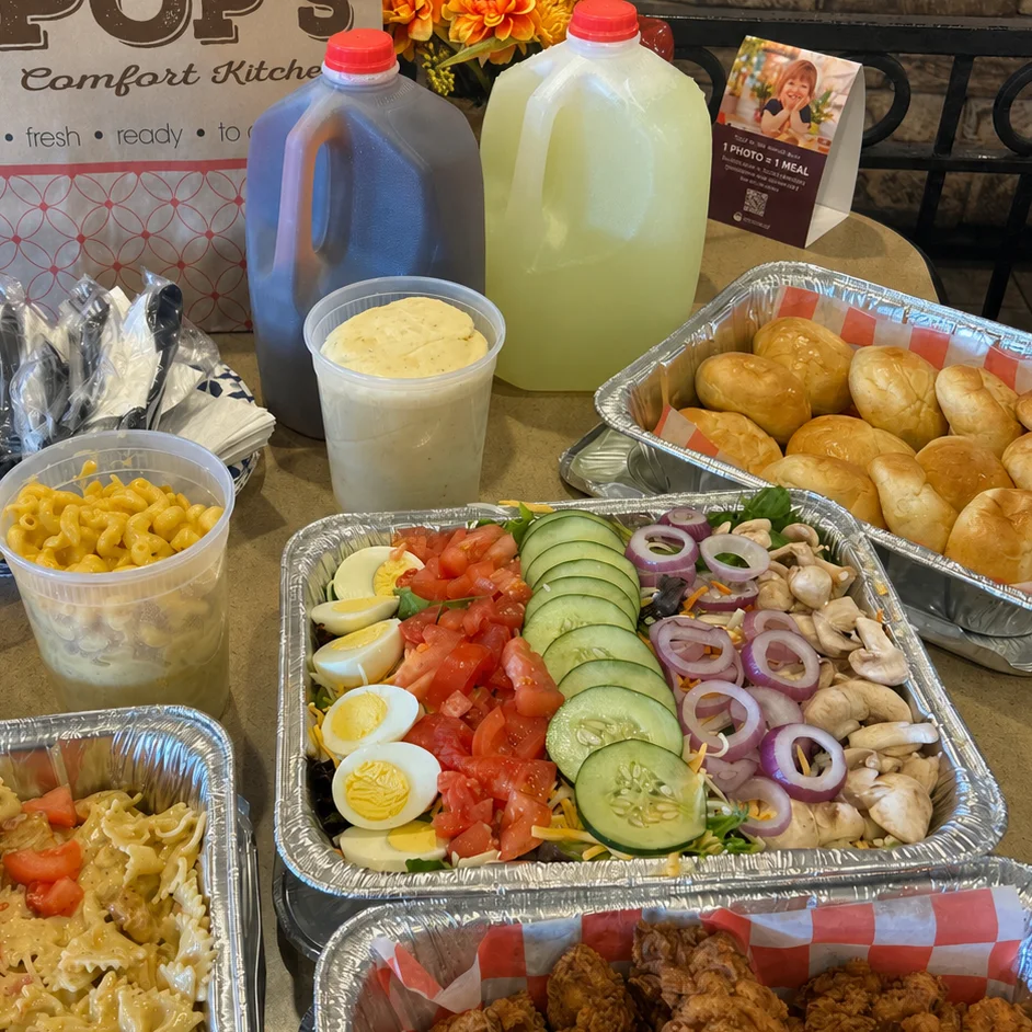 Assorted dishes: pasta, fried chicken, salad, sides, beverages