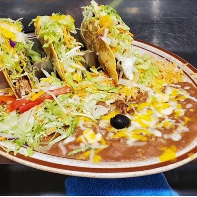Plate of Mexican tacos with refried beans and fresh toppings