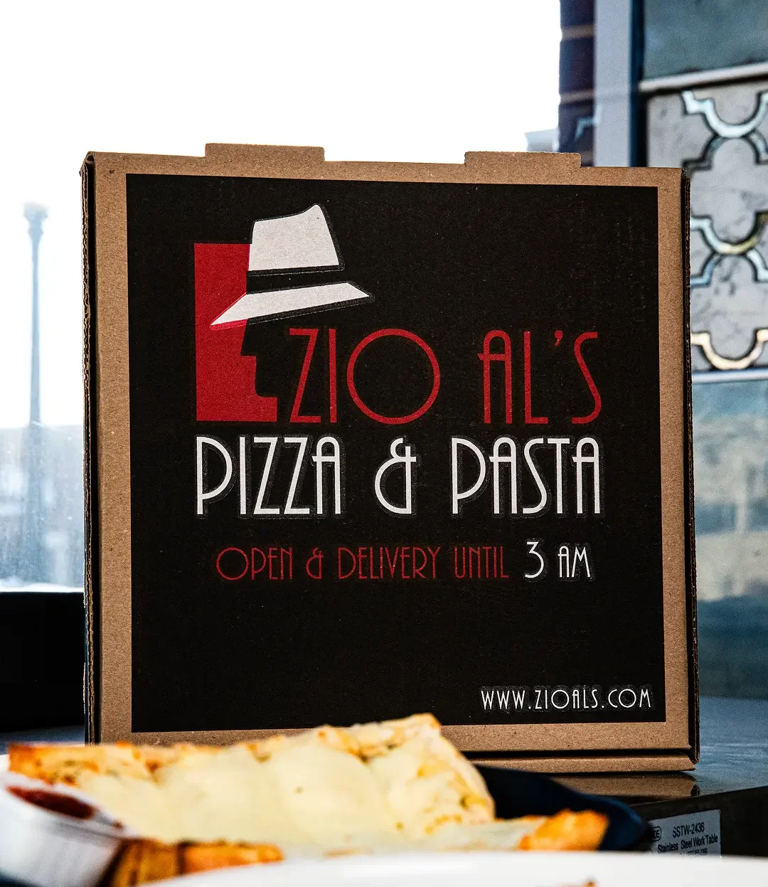 Zio Al's Pizza & Pasta delivery box with food items on a table.