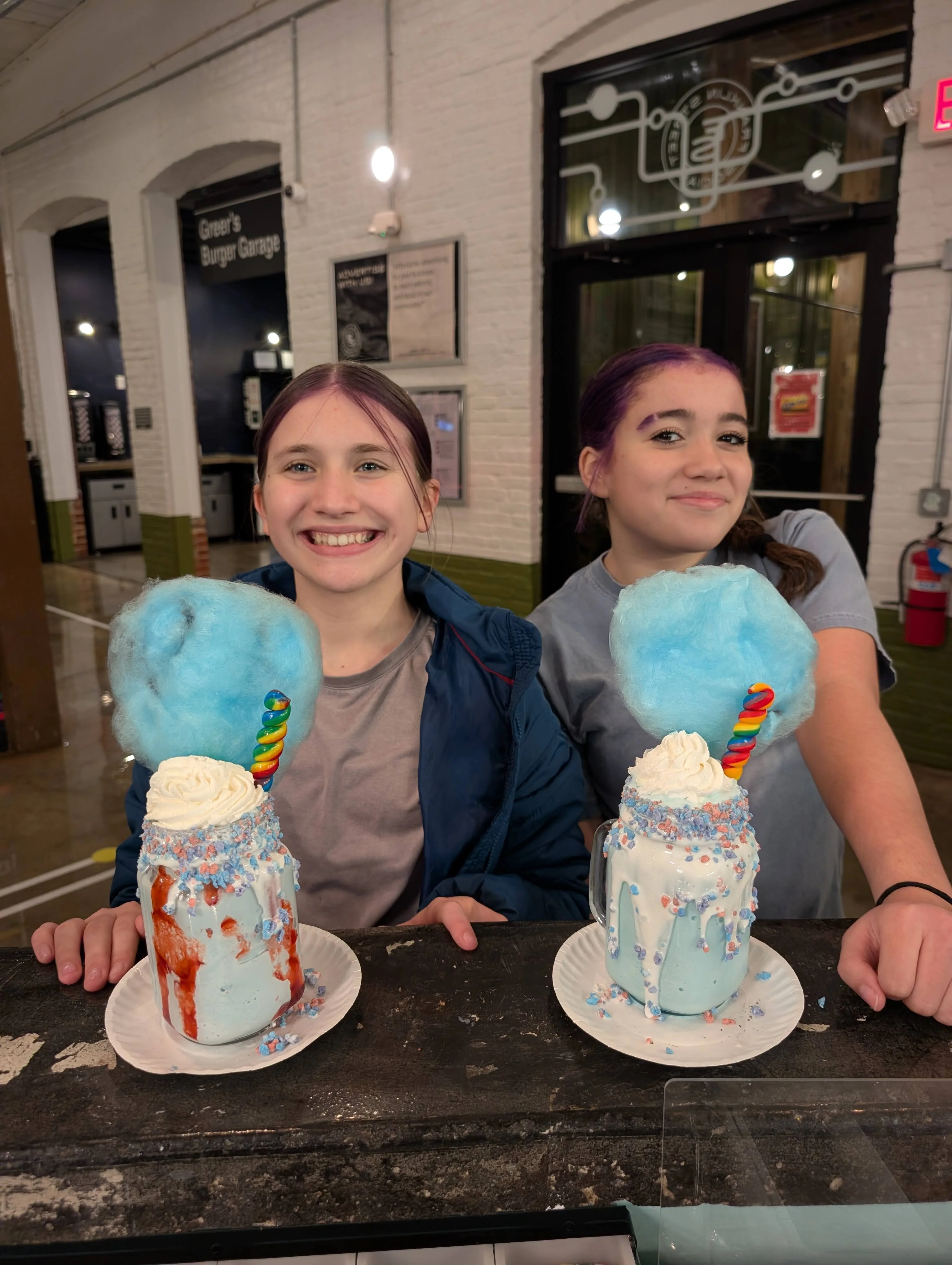 Colorful milkshakes topped with cotton candy and whipped cream