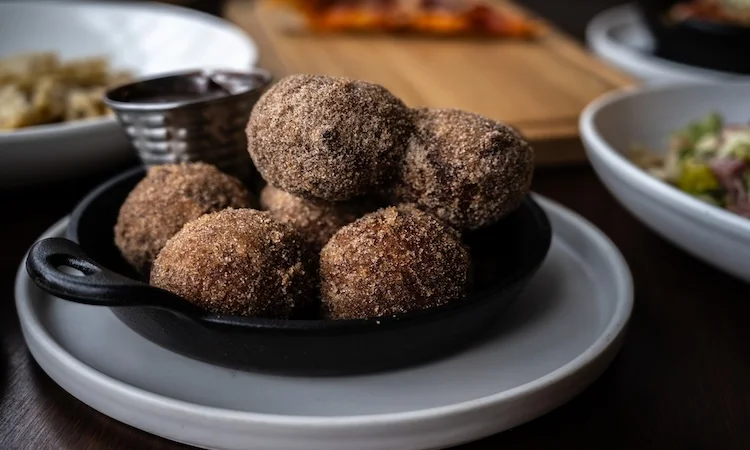 Delicious Spanish churros dusted with sugar in a cast iron dish