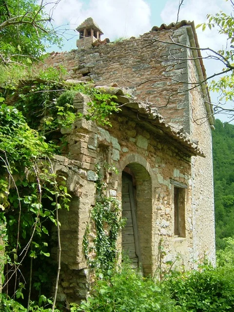 Abandoned stone house overgrown with greenery
