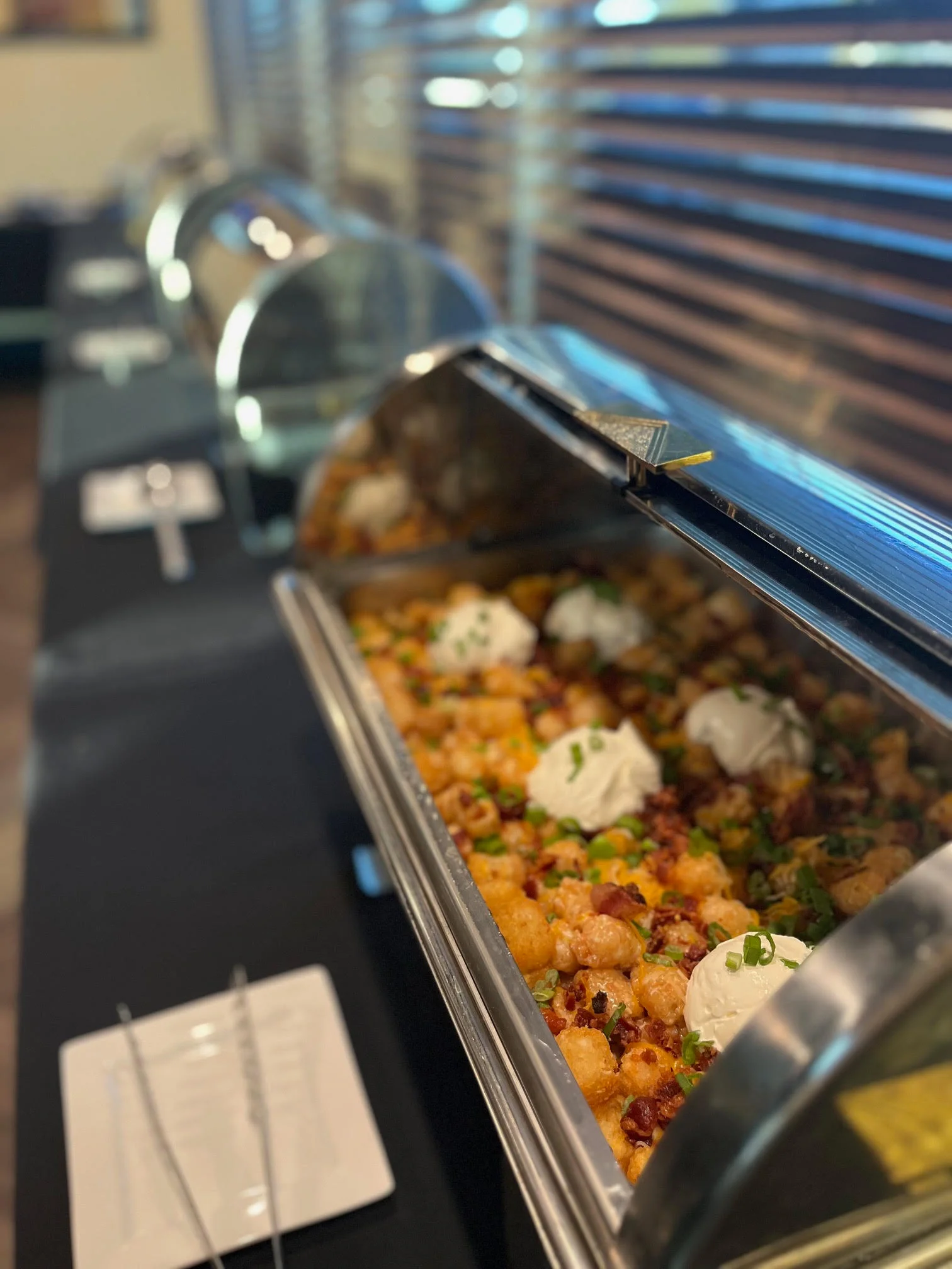 Loaded tater tots with toppings in a buffet setting