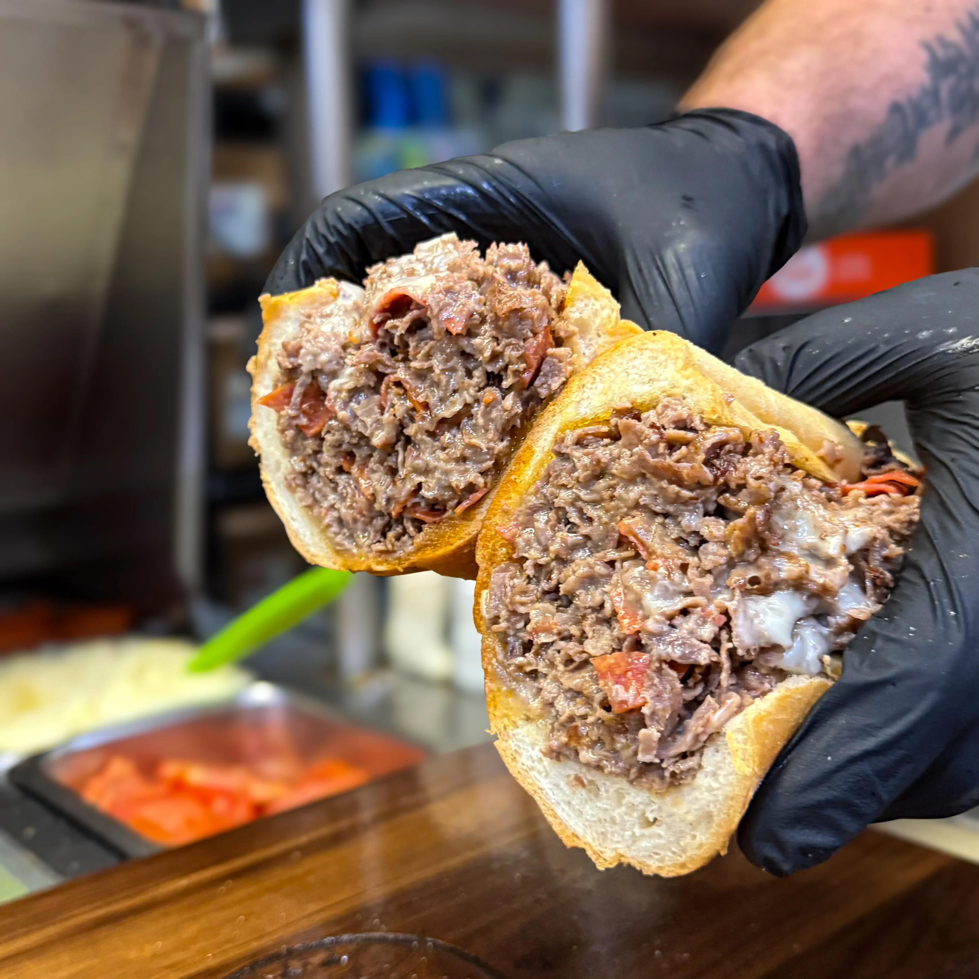 lf – Cheesesteak sandwich sliced open to show beef pepperoni, and cheese filling.