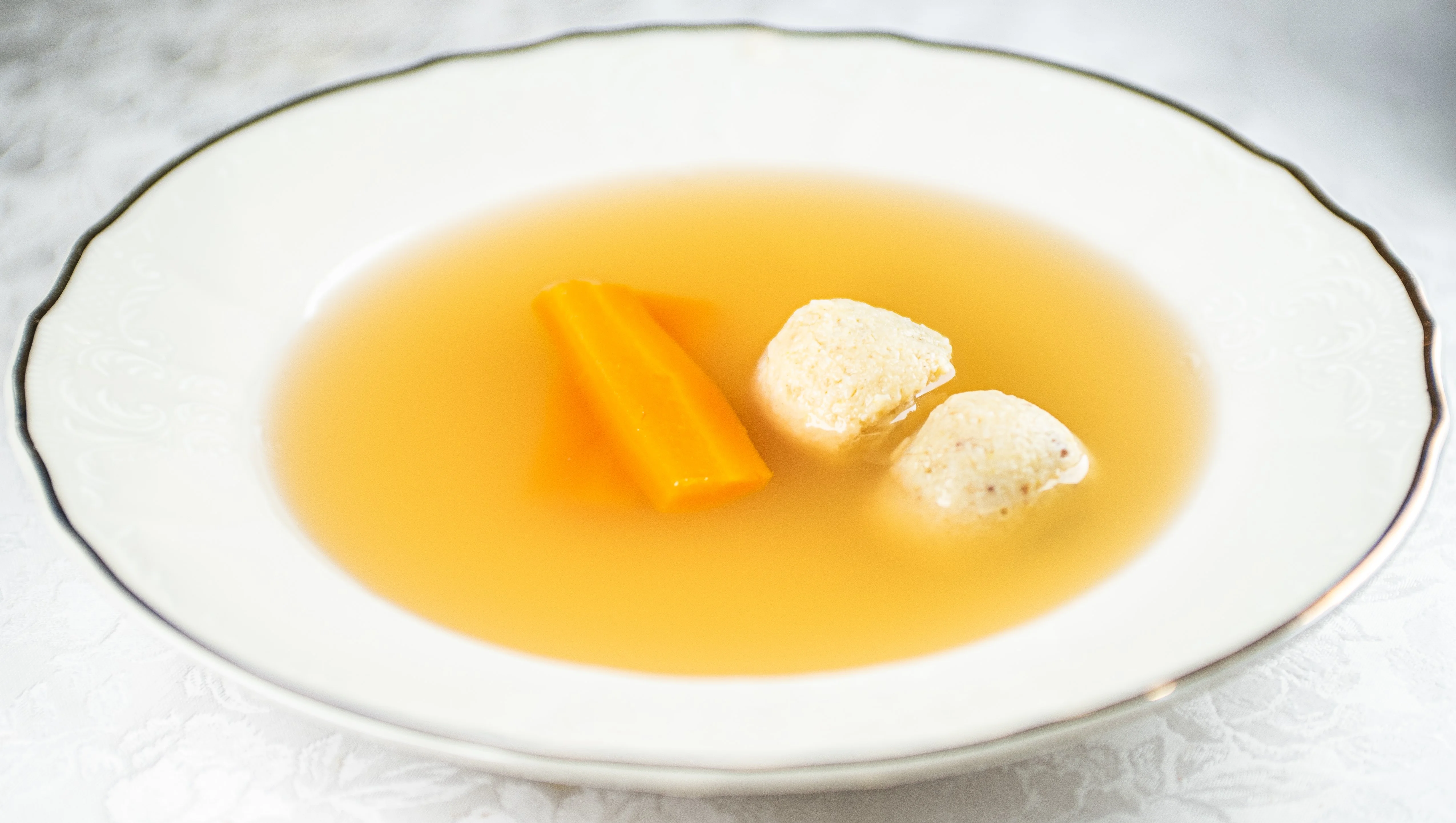 Traditional Jewish matzo ball soup in a decorative bowl