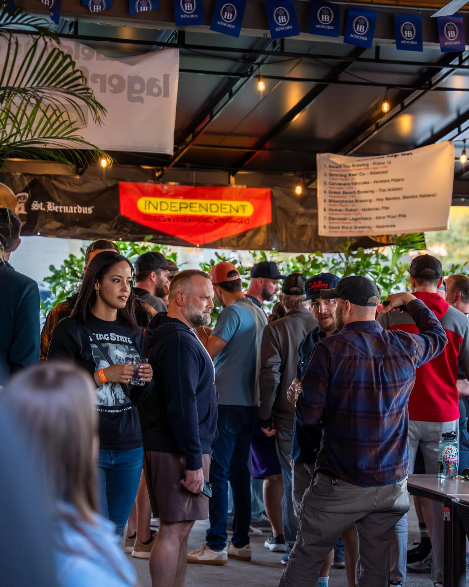 Crowd enjoying drinks at a lively outdoor bar event with banners.