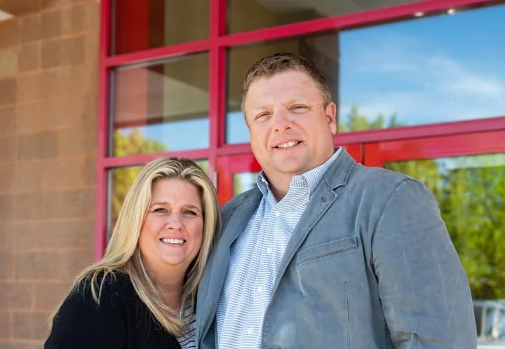 Couple posing outside a restaurant with large windows and red accents