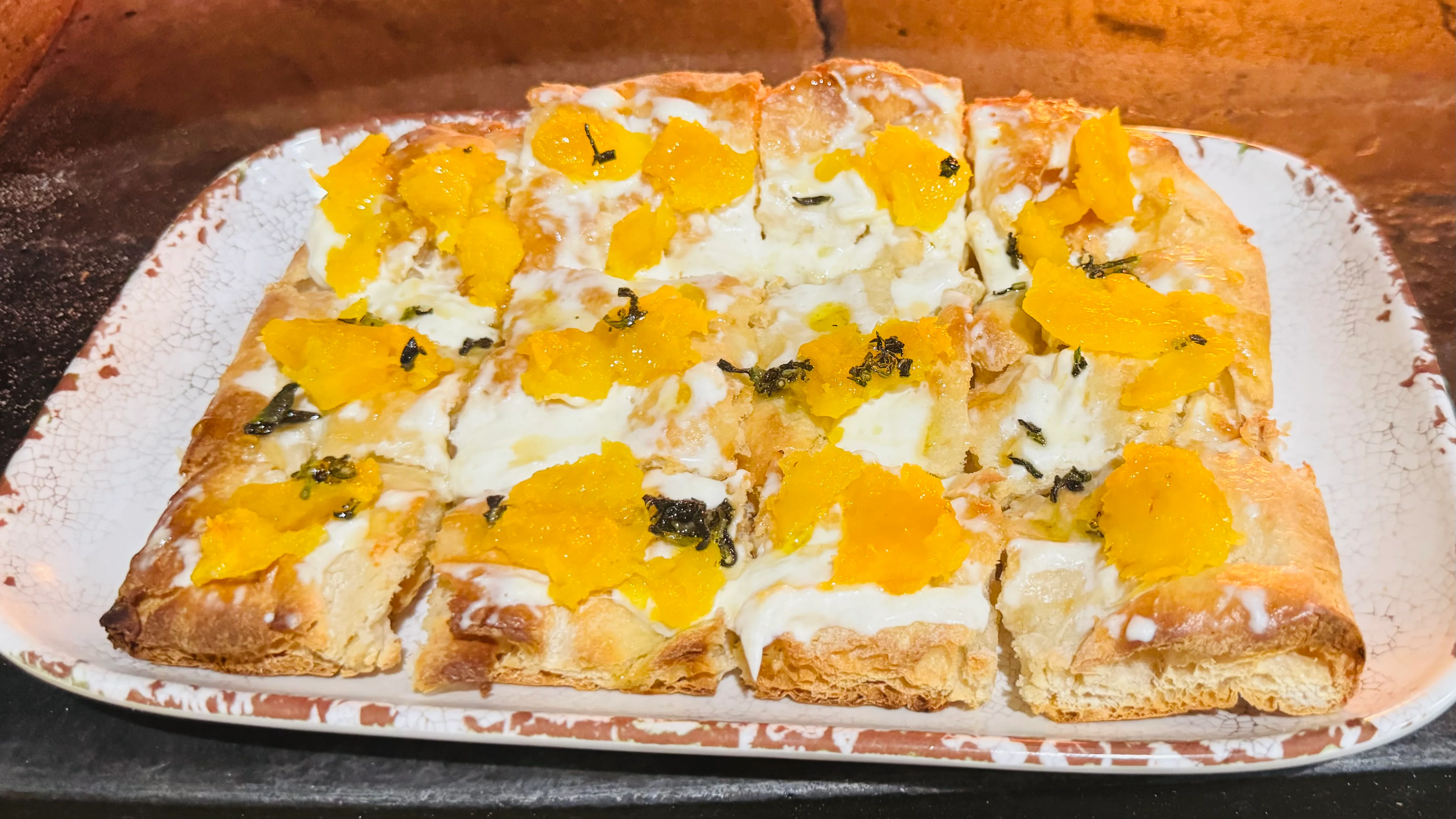 Wood fired pastry topped with mango, cream, and fresh herbs