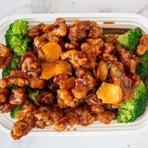 Sweet and sour chicken with broccoli in a takeout container