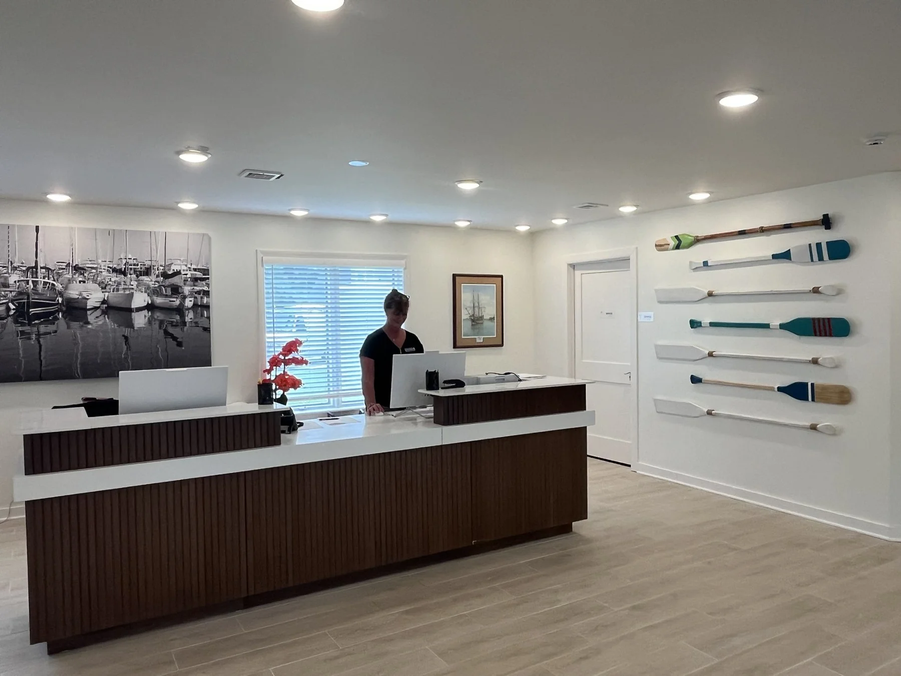Front desk at Hotel Manteo with a wall of painted oars and marina photography