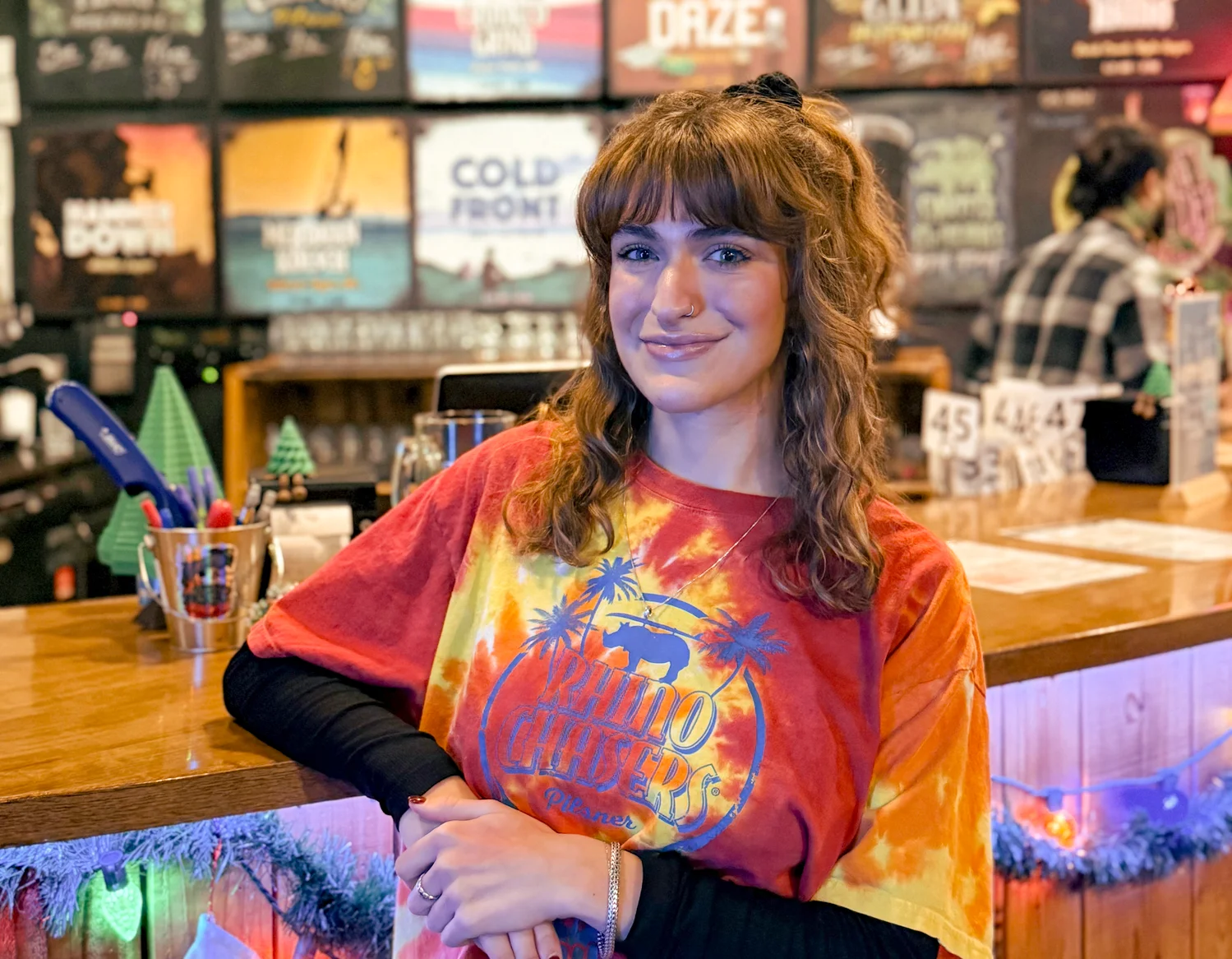Friendly bartender at a vibrant bar counter with colorful decor