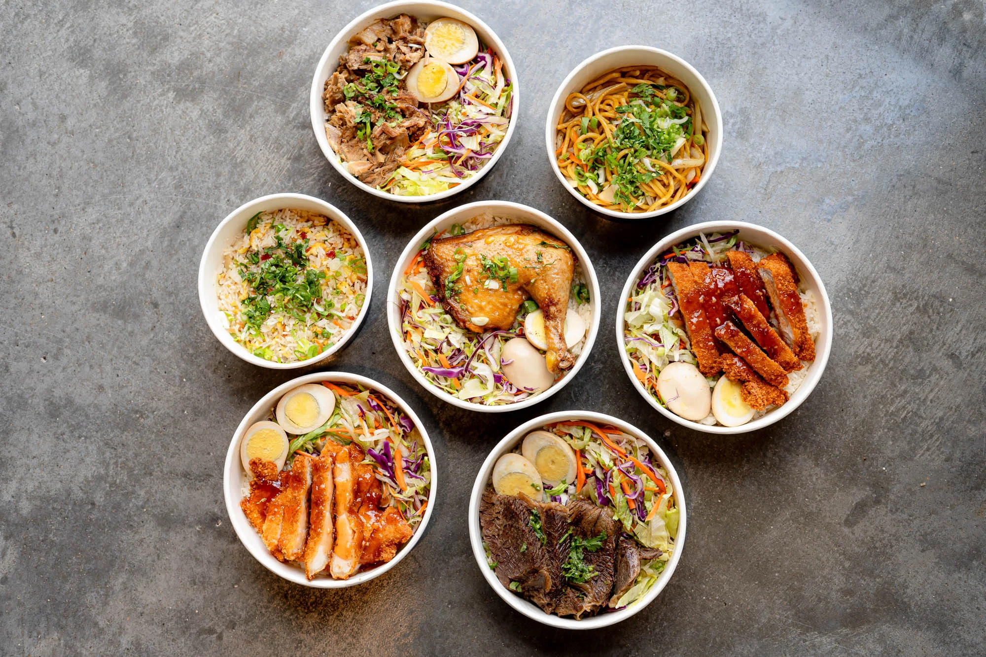Assorted Asian rice bowls with meats and vegetables