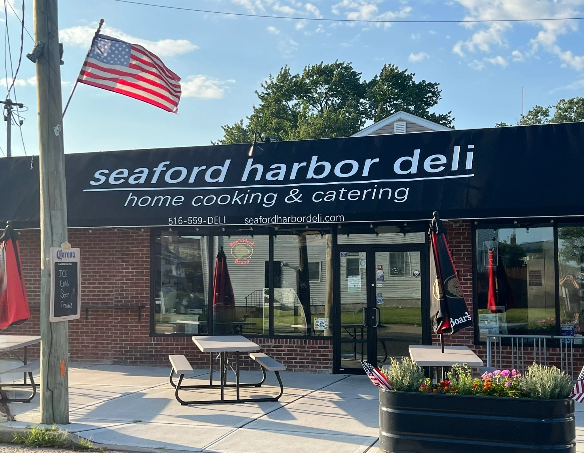 Exterior view of Seaford Harbor Deli with American flag and outdoor seating