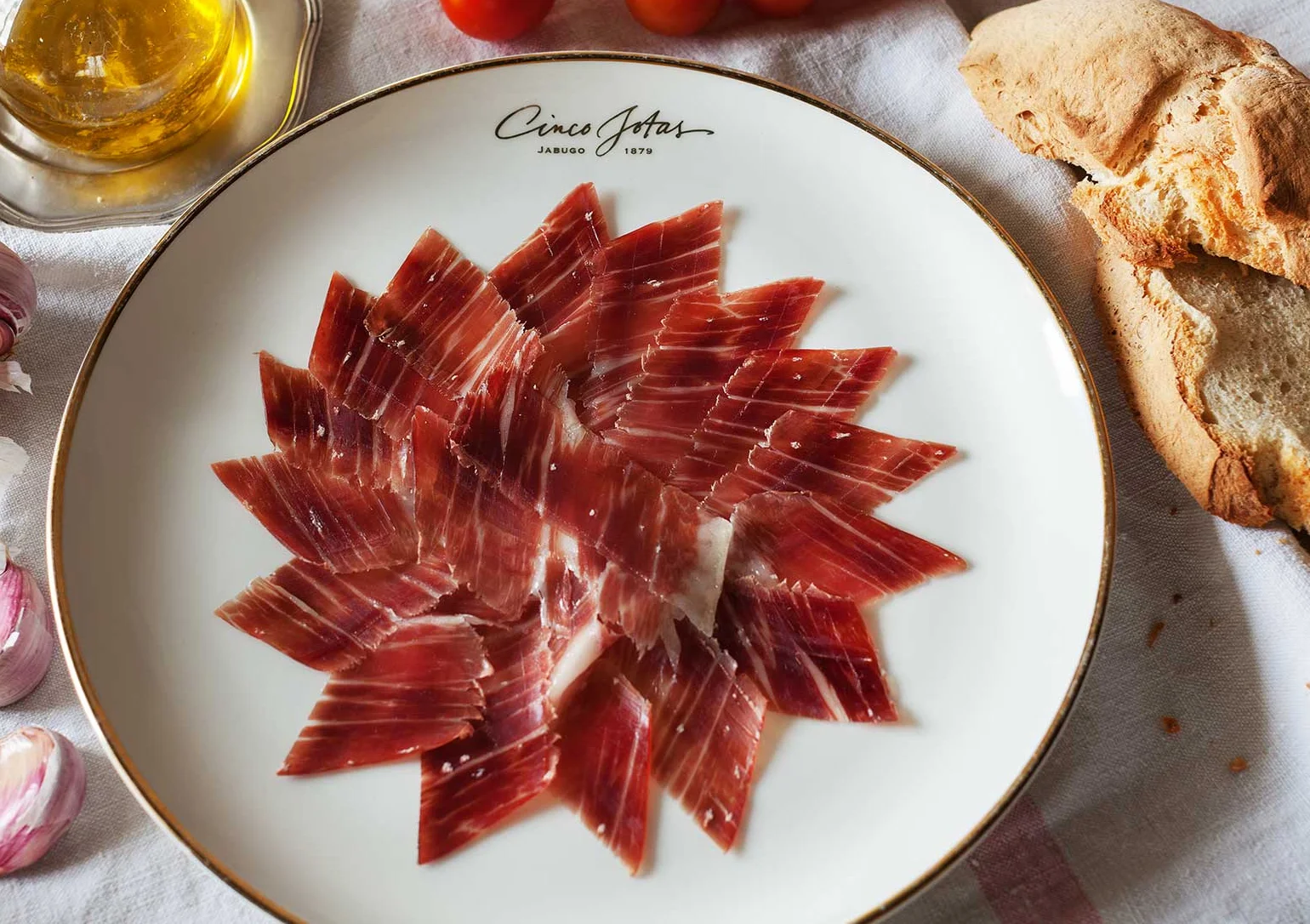 Thinly sliced Jamon Iberico, arranged in overlapping radial pattern on a white plate.