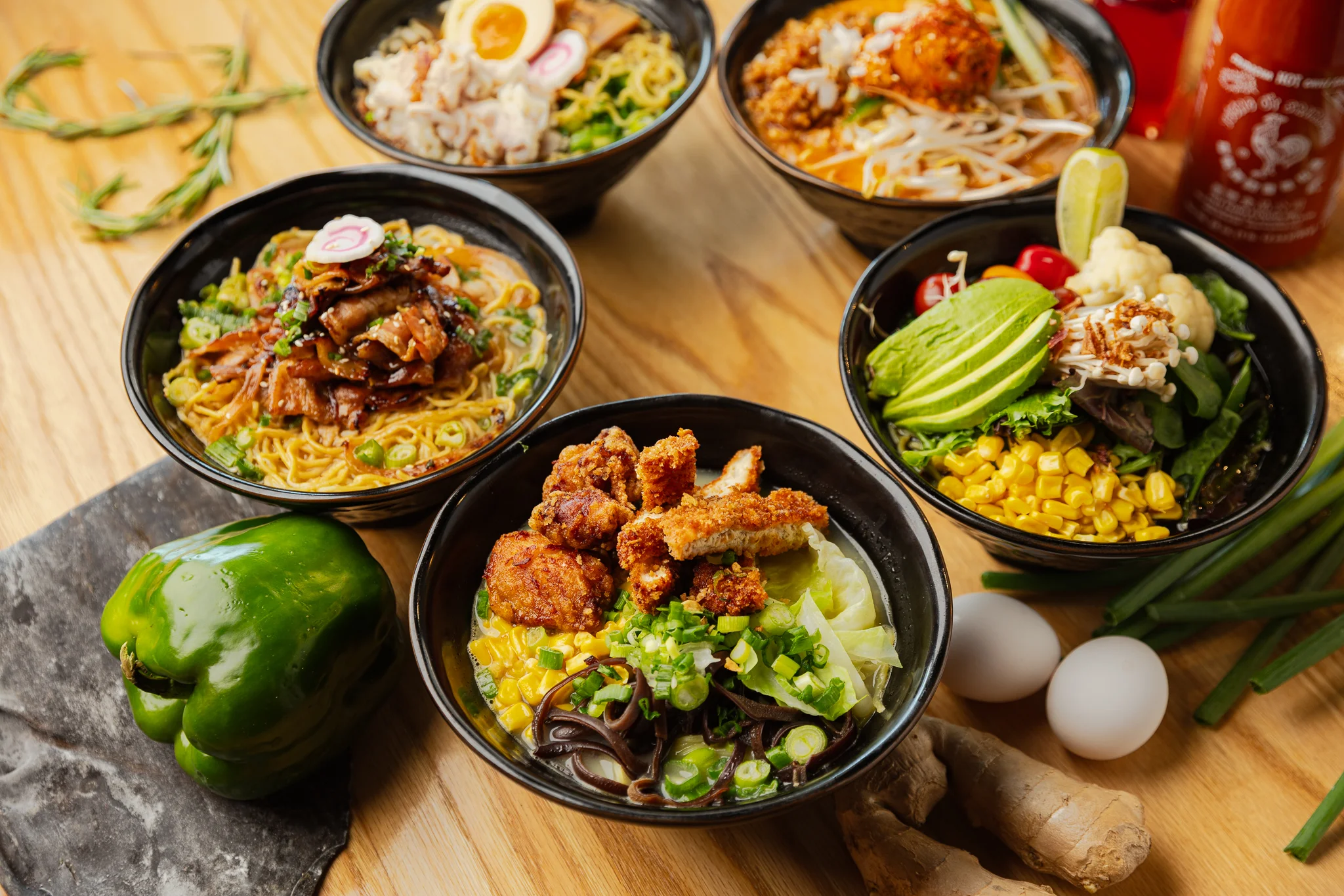 Assorted Asian noodle bowls with fried chicken and fresh vegetables