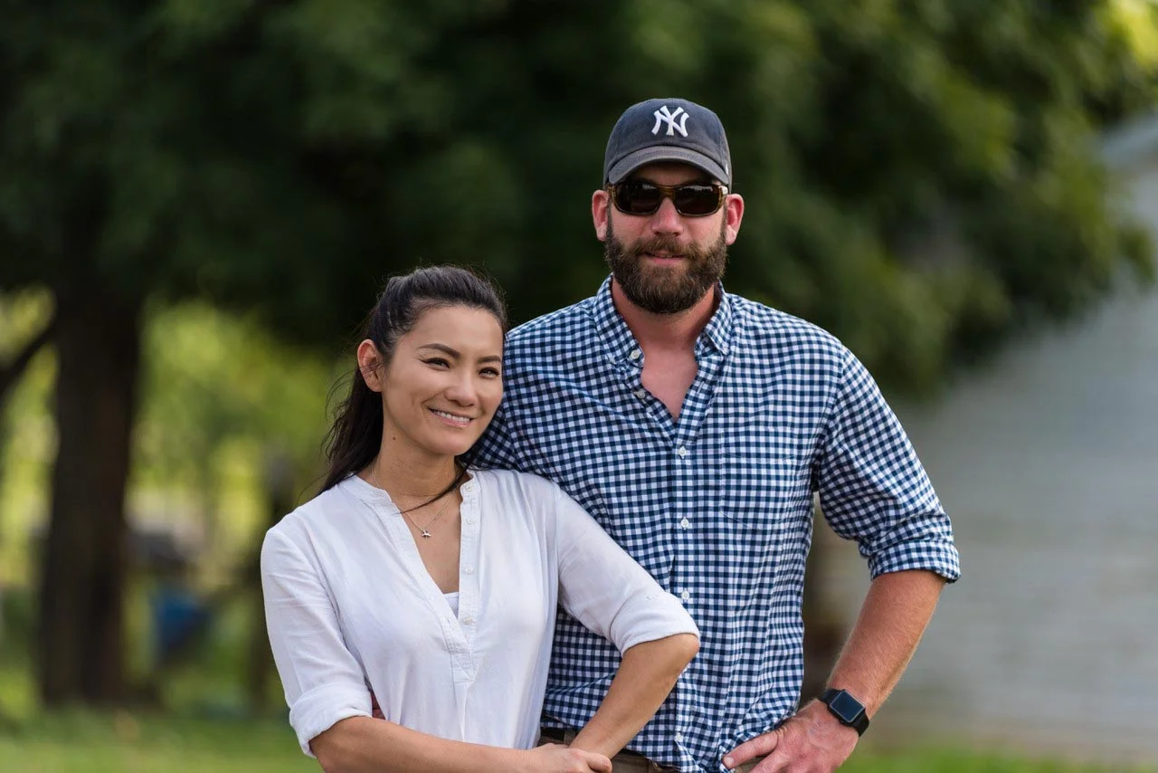 Couple posing outdoors with greenery in the background