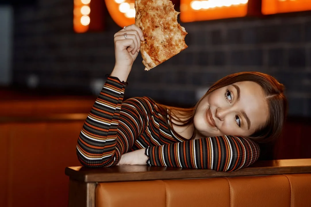 Young woman enjoying a slice of Margherita pizza in a cozy restaurant
