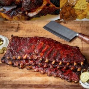 Full rack of smoked barbecue ribs on a wooden cutting board with a cleaver, served alongside pickles and classic soul food sides.