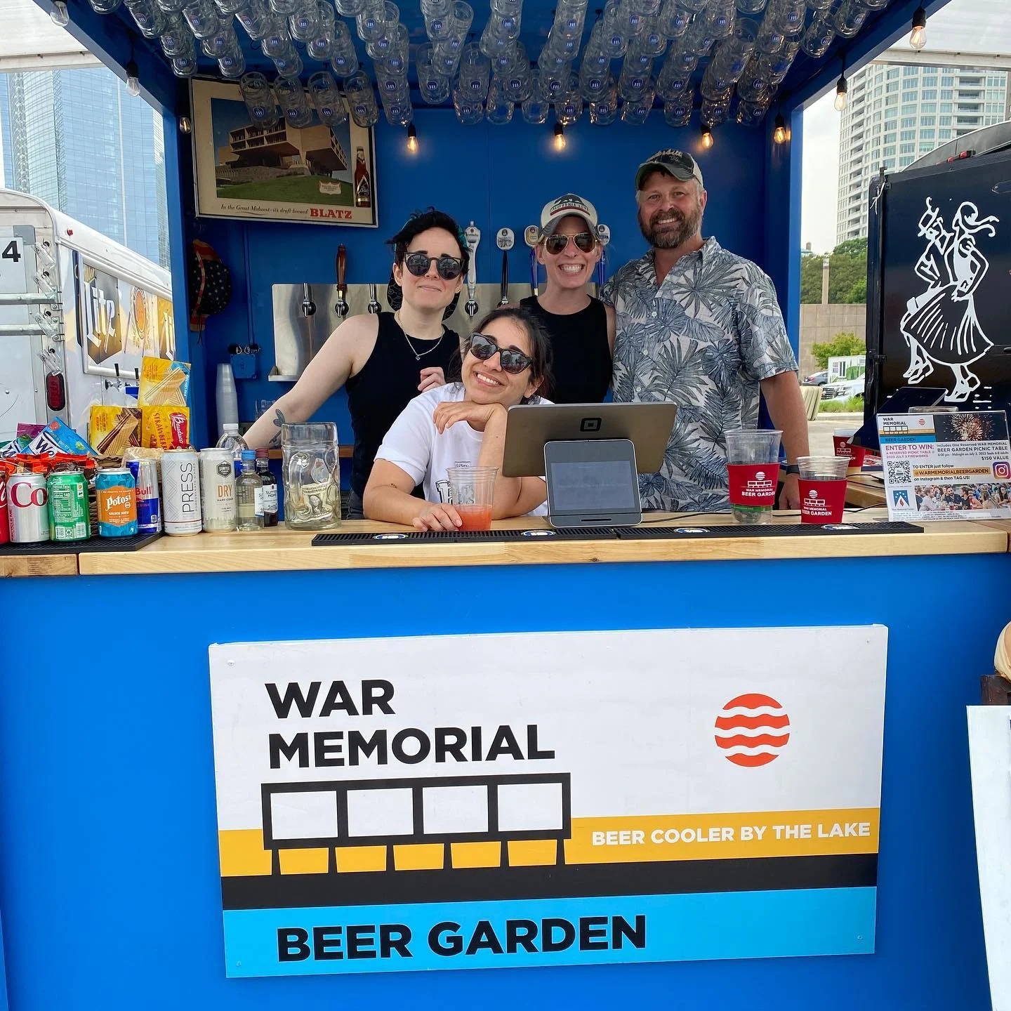 Staff at a vibrant beer garden bar with drinks and snacks