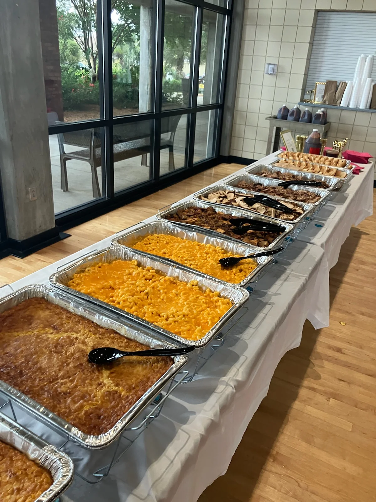 VooDoo BBQ catering setup with pans of mac and cheese, pulled pork, smoked chicken, and BBQ sides ready for events in Pensacola.
