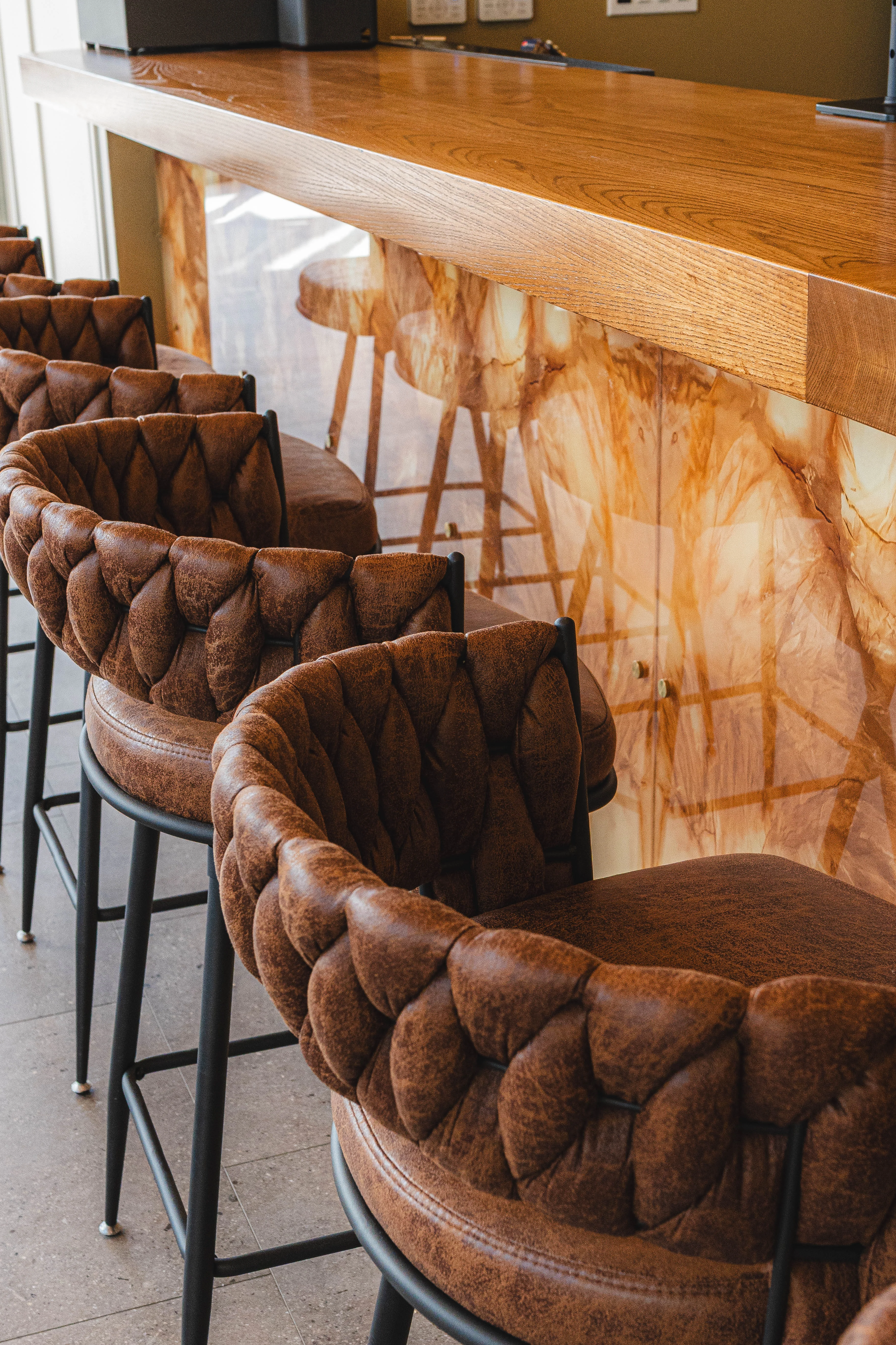 Stylish bar seating with tufted brown chairs and a wooden counter