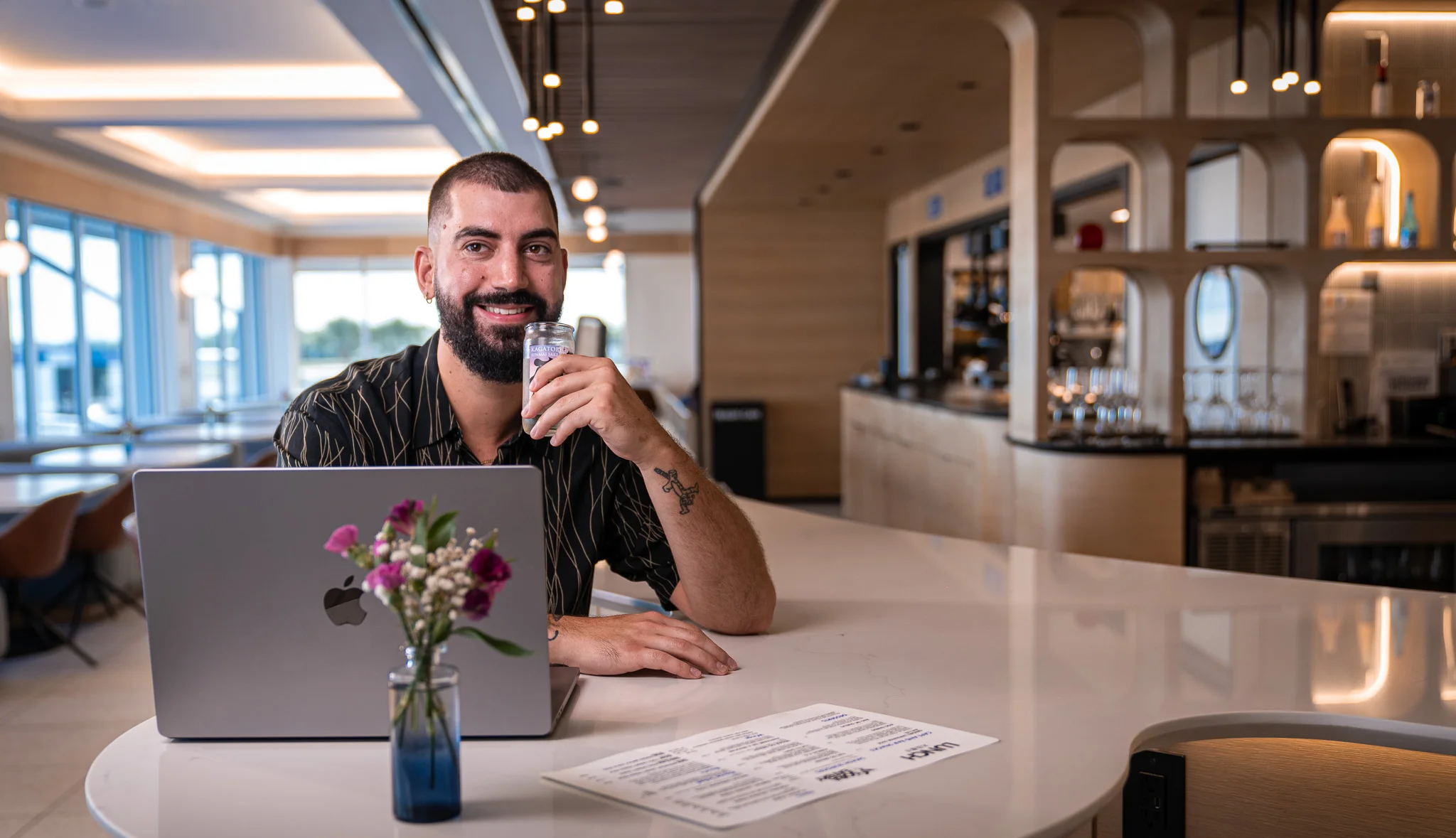 Modern restaurant interior with a man enjoying a drink and working on a laptop