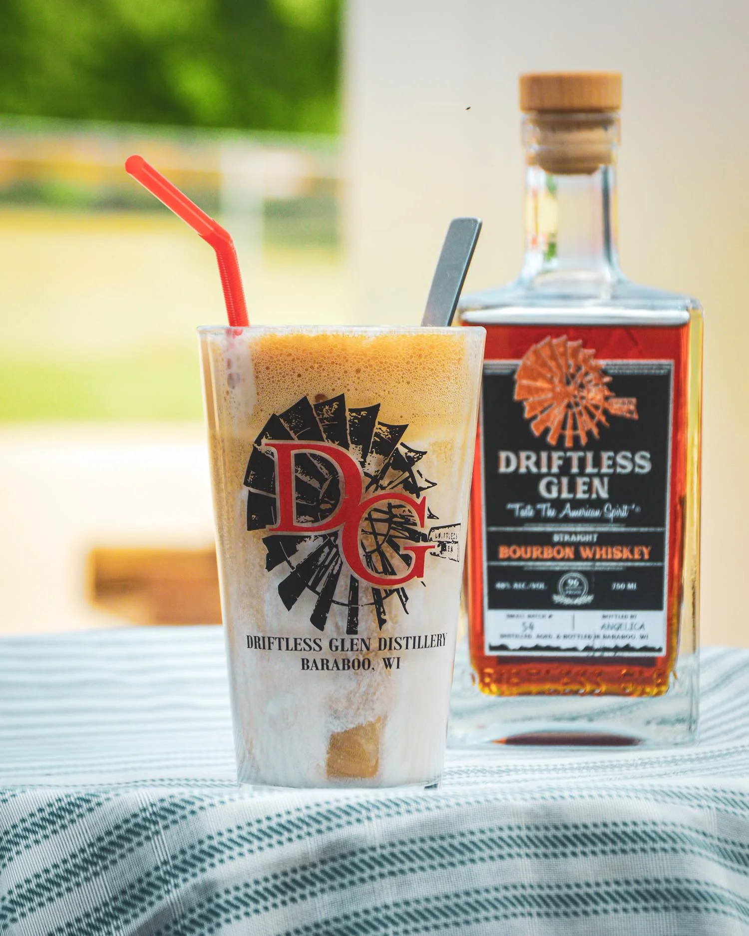 Root Beer Float outside on the patio with a bottle of Driftless Glen bourbon in the background