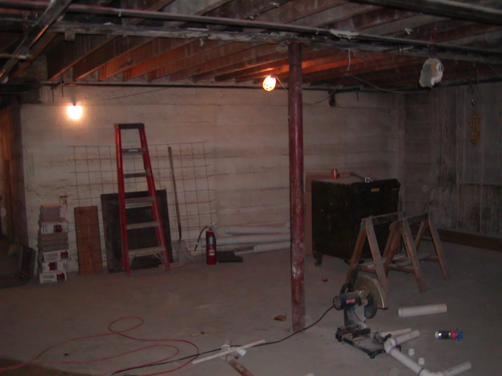 Empty basement space with construction tools and lighting