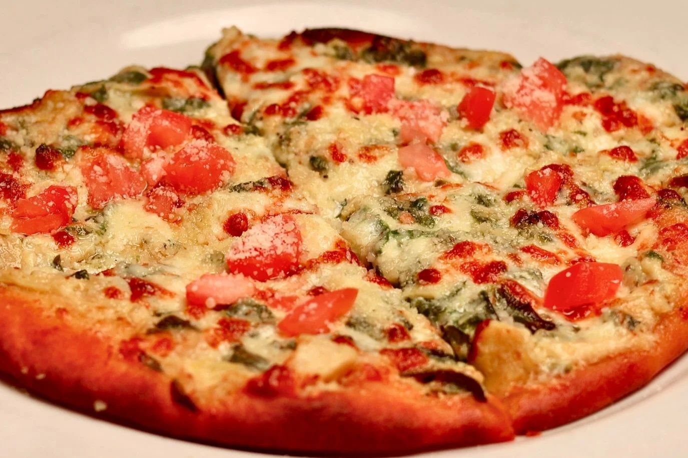 Delicious spinach and artichoke naan pizza topped with cheese.