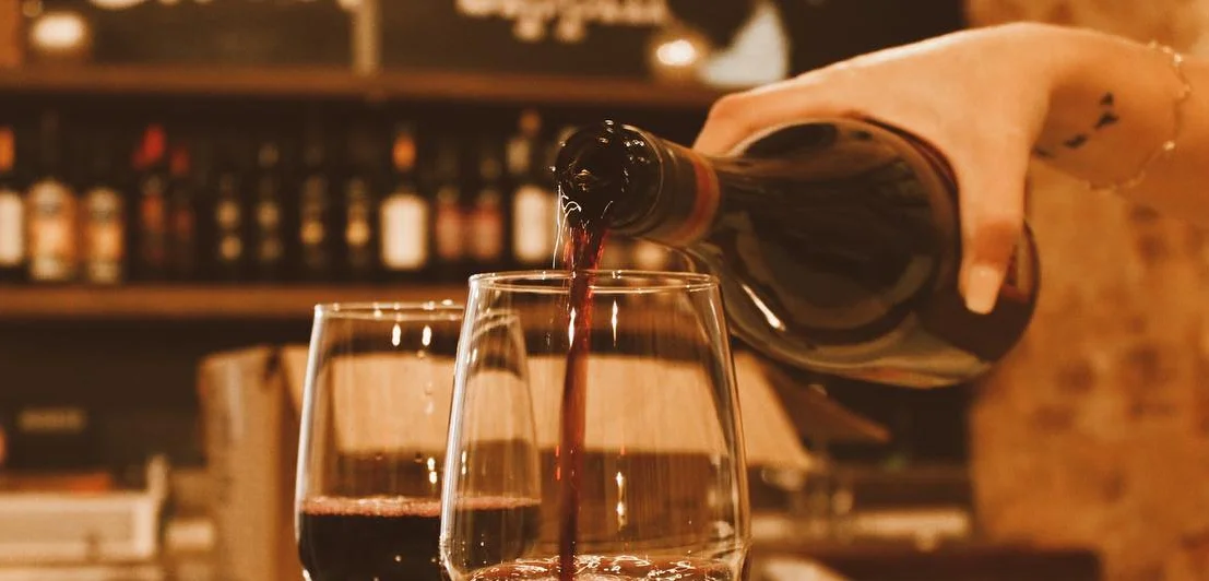 Pouring red wine into glasses at a cozy bar