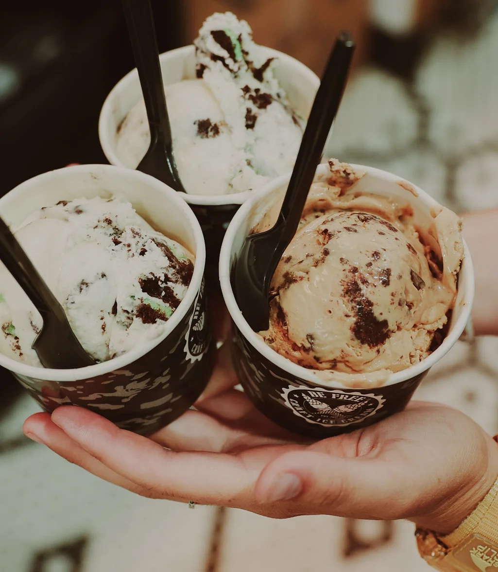 Three scoops of ice cream in cups, showcasing different flavors