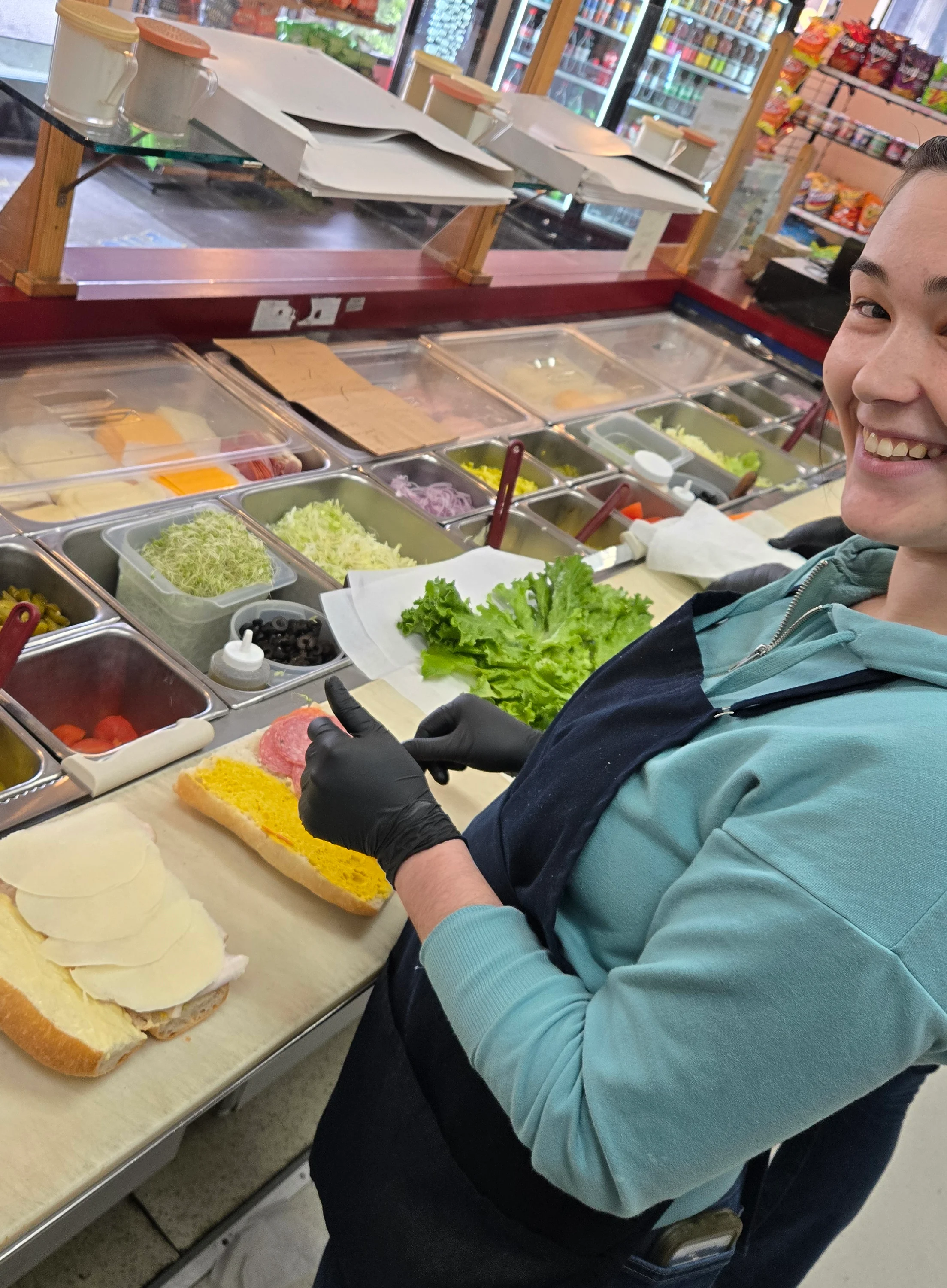 Sandwich preparation at a deli counter with fresh ingredients
