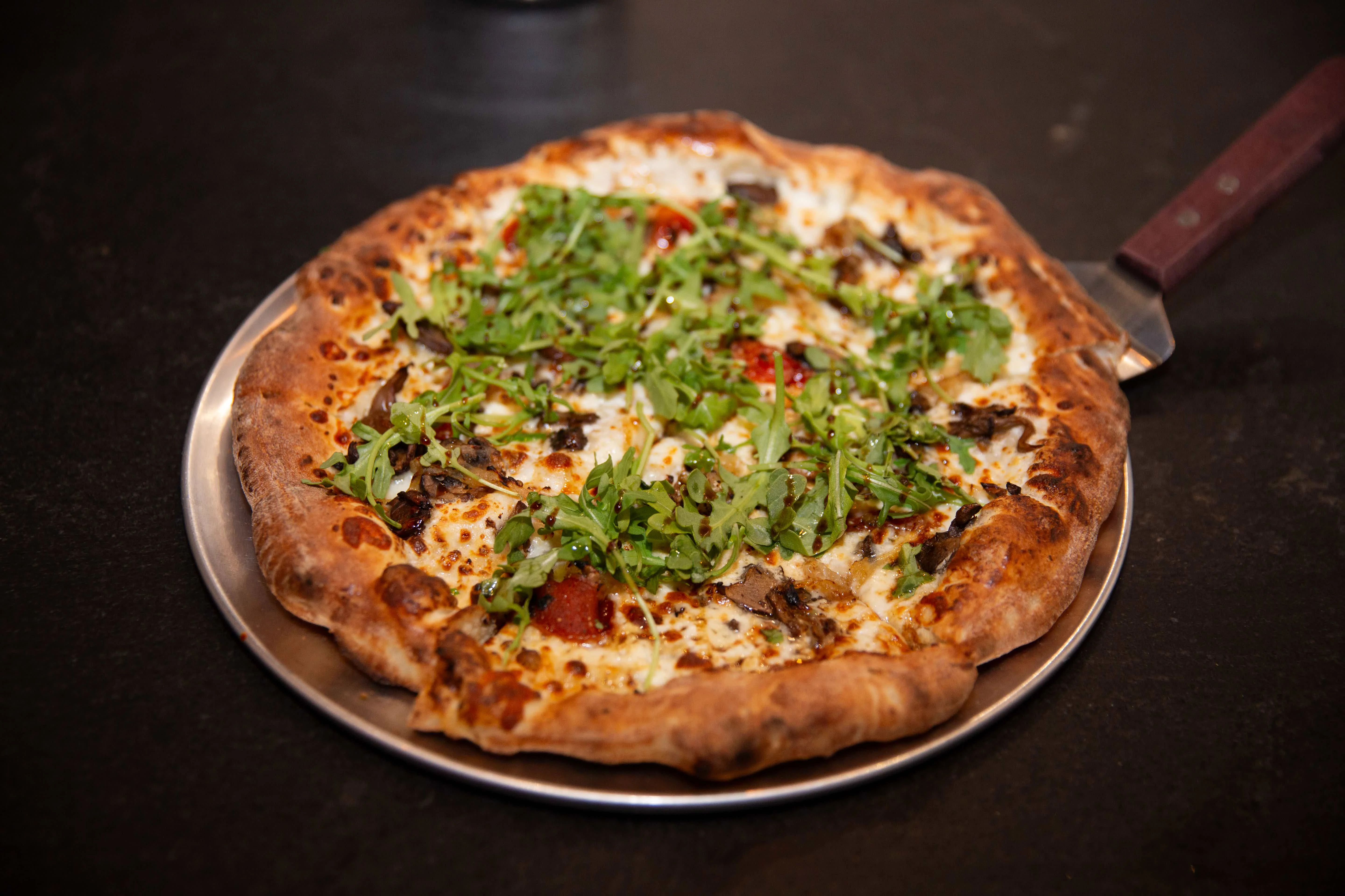 Wood-fired pizza topped with fresh arugula
