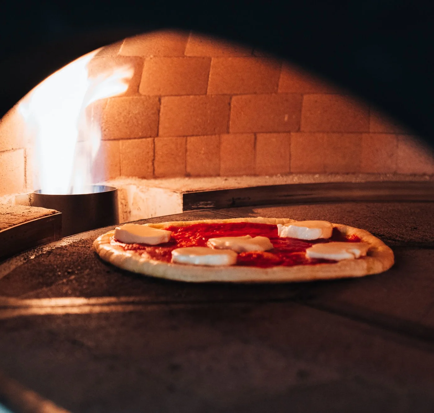 A margherita pizza baking in the Marra Forni stone oven at Firetender, the restaurant downstairs at Hotel Manteo in Manteo, NC