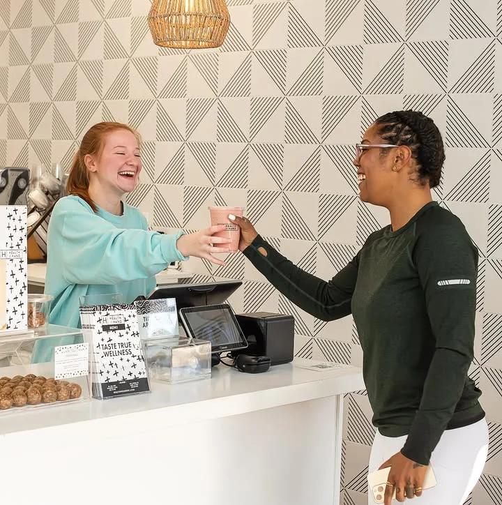 Happy barista serving coffee to a customer in a modern café